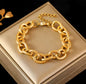 Gold chain link bracelet with textured finish displayed on a beige jewelry box
