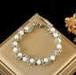 Silver chain bracelet with white pearls displayed on a beige box