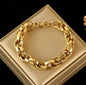 Gold-toned chain link bracelet with lobster clasp displayed on a beige jewelry box